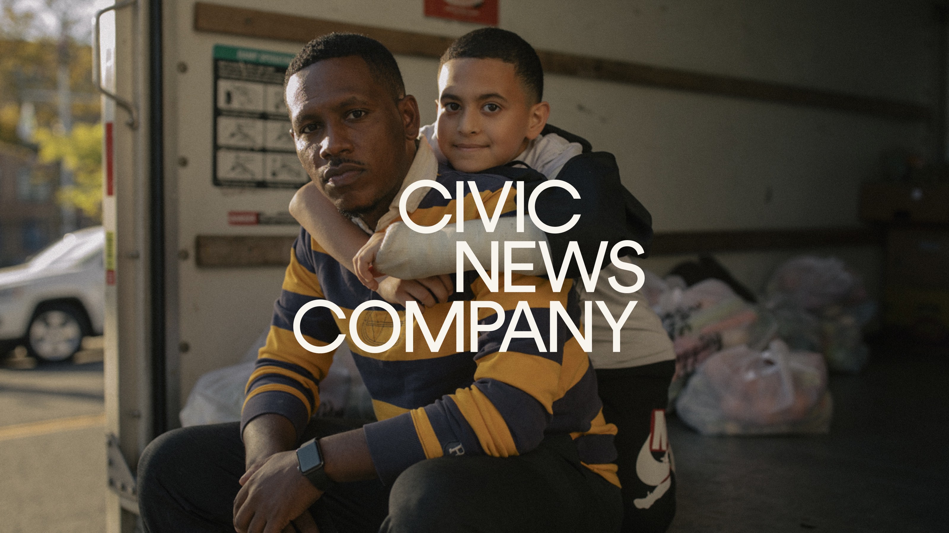 A journalistic photo of a father and son with the Civic News Company logo set above the image